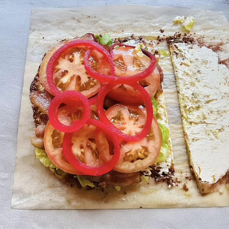 Zucchini breadwich stacked with chicken, cheese, and arugula, held in hand like a sandwich